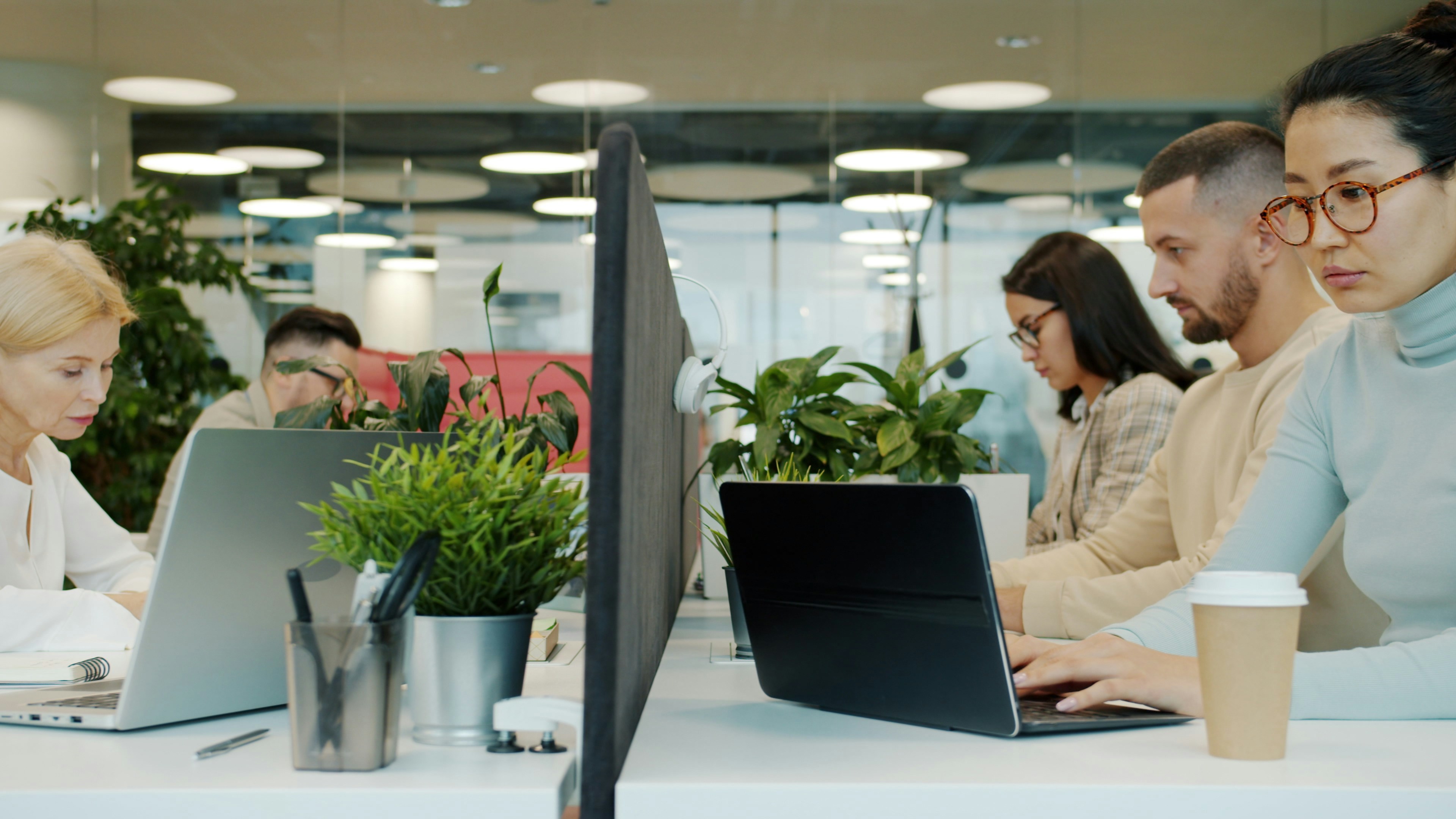 開放式辦公室中多位上班族久坐使用筆電工作，呈現久坐與外食族群日常情境，常見於關注兒茶素等日常營養補充的族群